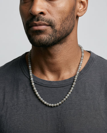 Man wearing a gray tones labradorite 6mm beaded necklace against a plain background