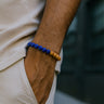 A close-up of a male model's wrist showcasing the bold 8mm scale and color contrast of a Lapis Lazuli and Sandalwood bracelet.
