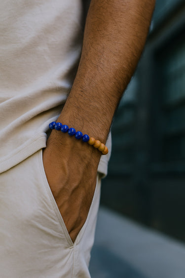 A close-up of a male model's wrist showcasing the bold 8mm scale and color contrast of a Lapis Lazuli and Sandalwood bracelet.
