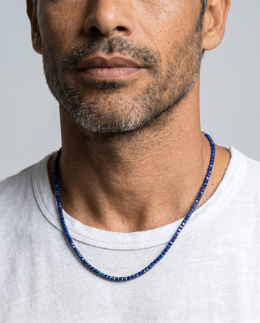 Man wearing a 3mm faceted lapis lazuli cube bead necklace with natural deep blue gemstones and a minimalist profile.