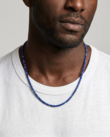 Man wearing a faceted lapis lazuli cube bead necklace featuring natural blue gemstones and a refined modern design.