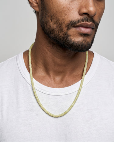 Man wearing a lemon jade heishi necklace against a plain background
