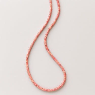 An angled view of a 4mm Rhodonite heishi bead necklace highlighting the smooth, seamless transition between the disc-shaped beads.
