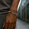 A close-up of a male model's wrist showcasing the eclectic, multi-tonal rhythm of a 4mm mixed gemstone heishi bead bracelet.
