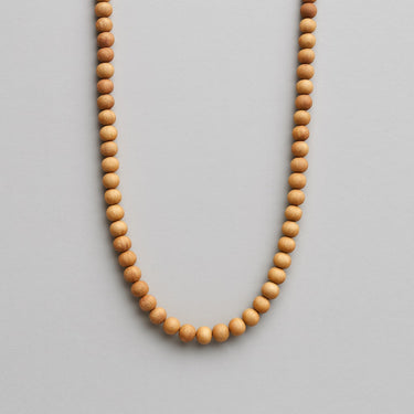 A strand of 6mm round golden sandalwood beads displayed in a U-shape against a neutral background.
