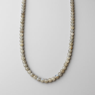 A strand of 6mm round labradorite beads showing natural grey and blue tones, displayed in a U-shape against a neutral background.

