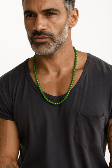 A male model wearing a dark grey t-shirt showcasing the rich green tones of a 6mm Nephrite Jade beaded necklace.
