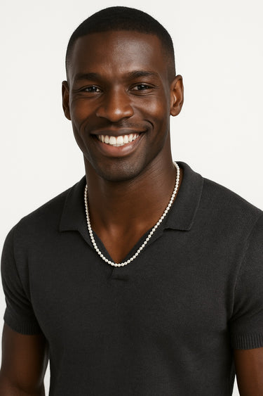 A smiling male model in a black polo shirt showcasing a 4-5mm freshwater pearl necklace.
