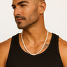 A man in a black ribbed tank top wearing a strand of 4-5mm white freshwater pearls.
