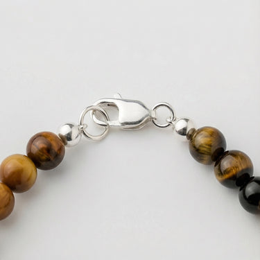 Close-up of a men’s necklace with 6mm tiger's eye beads and a polished sterling silver lobster clasp.