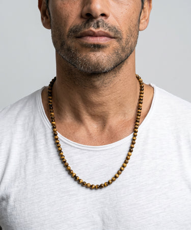 Man wearing a 6mm tiger's eye beaded  necklace against a plain background