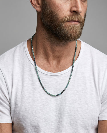 Man wearing a 3mm faceted tourmaline cube bead necklace with natural multi-color tourmaline and a minimalist silhouette.