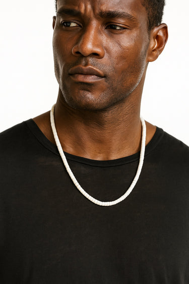 A male model wearing a black t-shirt showcasing the high-contrast look of a 4mm white turquoise heishi necklace.
