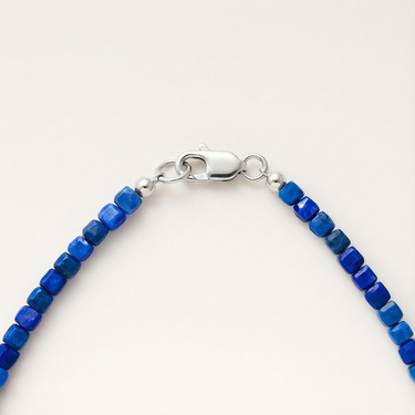 Macro view of blue lapis faceted cube beads finished with a high-polish silver lobster clasp.