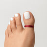 Red anodized aluminum toe ring worn on big toe — alternate angle showing adjustable open-band fit, COLORS collection by Clay & Chloe Jewelry.
