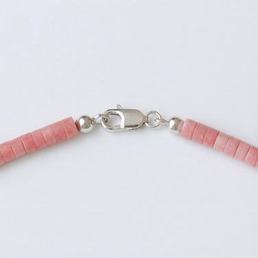A macro close-up view of 4mm pink Rhodonite heishi beads finished with a high-polish silver lobster clasp.
