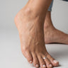 Close-up of a foot with a toe ring on a neutral background