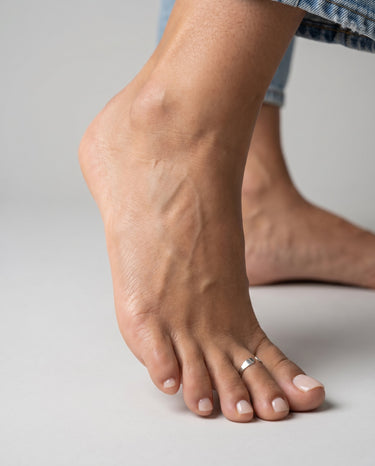 Close-up of a foot with a toe ring on a neutral background