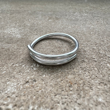 Silver adjustable overlap big toe ring on concrete surface