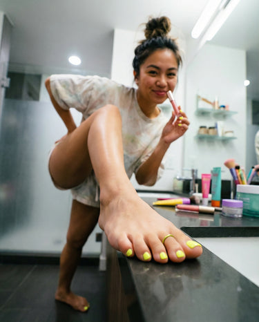 Woman showing off her toe ring with one foot on the bathroom counter 
