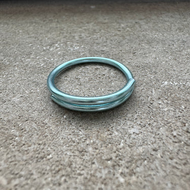 Sorbet blue anodized aluminum overlap toe ring displayed on concrete surface — lightweight water-friendly COLORS design.
