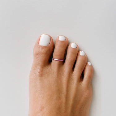 Sorbet pink anodized aluminum toe ring displayed on stone surface — smooth finish and pastel tone from the COLORS Collection.