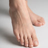Close-up of a foot wearing a silver beaded toe ring on a neutral background