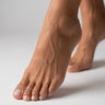 Close-up of a foot with a sterling silver toe ring on the secind toe on a neutral background