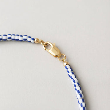 A macro close-up view of layered chevron glass beads finished with a high-polish gold lobster clasp.
