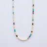 A product shot of multi-colored heishi bead necklace with accent heishi beads including turquoise, amethyst, and jade with sterling silver spacers, displayed in a U-shape.
