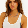 A lifestyle shot of a woman wearing the 2-3mm vintage chevron glass necklace, showcasing the delicate scale and vibrant blue tones against a white tank top.
