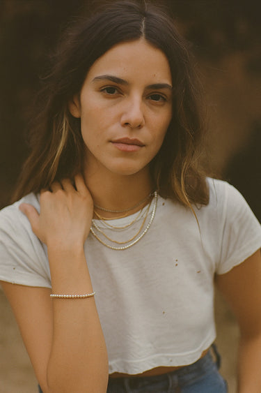 A lifestyle portrait of a model featuring the 2.5mm sterling silver cube chain bracelet and matching necklace, emphasizing the cohesive, sophisticated drape of the geometric chain design.
