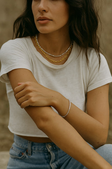 A lifestyle image of a model wearing the 2.5mm sterling silver cube chain bracelet, demonstrating its delicate yet structural presence and versatility for everyday styling.
