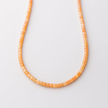 A studio view of a women's 2mm faceted sunstone cube necklace curved in a U-shape, highlighting the uniform geometric cut and vibrant orange tones.
