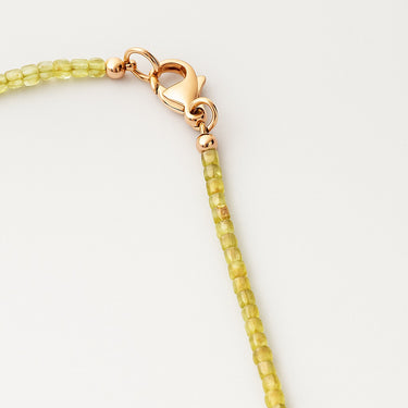 A macro detail shot of 2mm faceted peridot cube beads meeting professional-grade 14K gold-filled hardware, featuring a secure lobster clasp.

