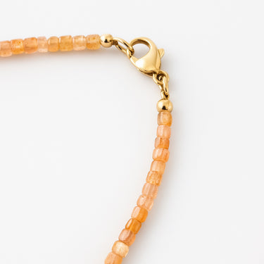 A macro detail shot of 2mm faceted orange sunstone cube beads meeting professional-grade 14K gold-filled hardware and a secure lobster clasp.
