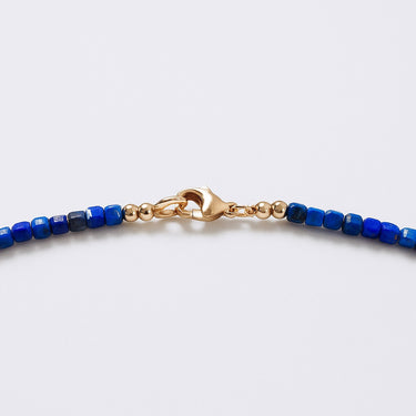 A macro close-up focusing on the 14K gold-filled lobster clasp and the precise geometric facets of the 3mm Lapis Lazuli cube beads.
