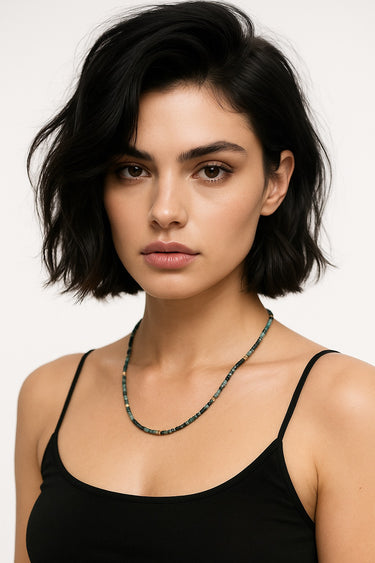 A lifestyle shot of a model wearing the 3mm faceted Tourmaline cube necklace against a black top, highlighting the stone's rich color palette and geometric texture.
