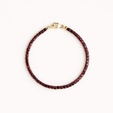 A studio hero shot of a women's 3mm natural faceted garnet cube bead bracelet with a 14K gold-filled clasp, highlighting the light-catching facets and deep wine-red gemstone tones.
