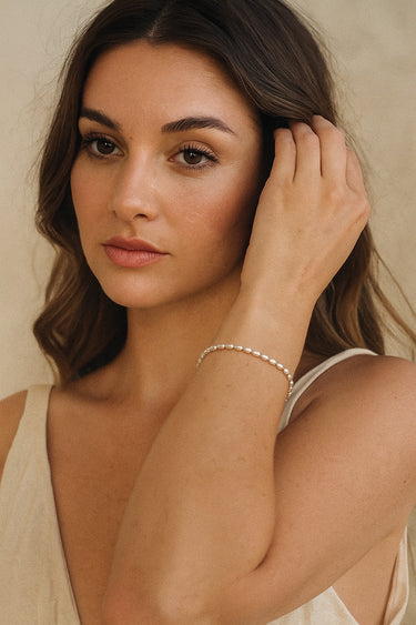 A lifestyle portrait of a model wearing the 3mm sterling silver oval rice chain bracelet, highlighting its delicate texture and minimalist aesthetic for everyday luxury.
