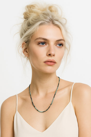 An editorial portrait of a woman wearing the 3mm tourmaline cube necklace, showcasing its sophisticated, industrial-refined edge and minimalist silhouette.

