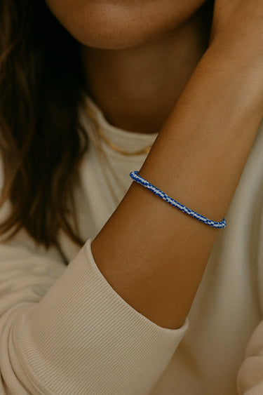 A lifestyle shot of a model wearing a women's 3mm vintage African chevron glass bead bracelet, highlighting the intricate blue and white patterns and structural silhouette.
