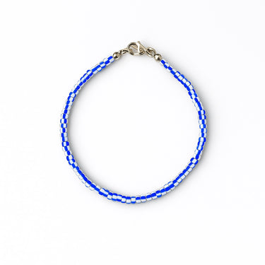 A studio hero shot of a 3mm vintage African chevron glass bead bracelet arranged in a clean circle, showcasing the unique artisanal details and sophisticated blue tones.
