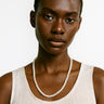 A woman wearing a 4-5mm freshwater pearl necklace, showcasing the delicate scale and luminous quality of the pearls against a white tank top.
