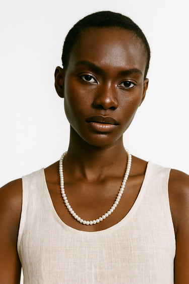 A woman wearing a 4-5mm freshwater pearl necklace, showcasing the delicate scale and luminous quality of the pearls against a white tank top.
