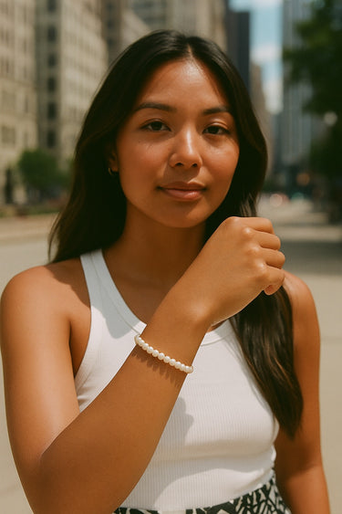 A portrait lifestyle image of a model featuring the dainty white baroque pearl bracelet, highlighting its sophisticated silhouette and modern artisanal style.
