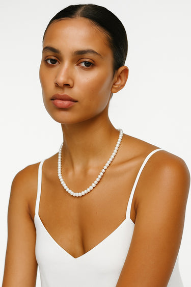 A woman wearing the 4-5mm freshwater pearl necklace, emphasizing its editorial silhouette and the modern, industrial edge of the design.
