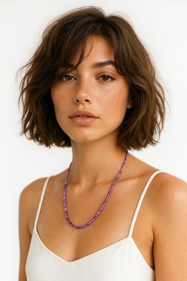 A studio shot of the women's 4mm amethyst heishi necklace curved in a U-shape, highlighting the uniform, tactile texture of the purple stone discs.
