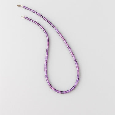 An overhead view of the 4mm amethyst heishi necklace arranged in a fluid S-curve, showcasing the natural color gradients within the gemstone beads.
