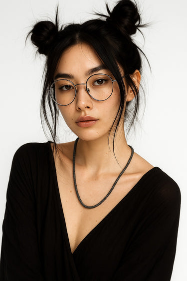 A lifestyle shot of a female model wearing a 4mm Black Lava heishi bead necklace, showcasing its tactile matte surface and sleek, minimalist profile.
